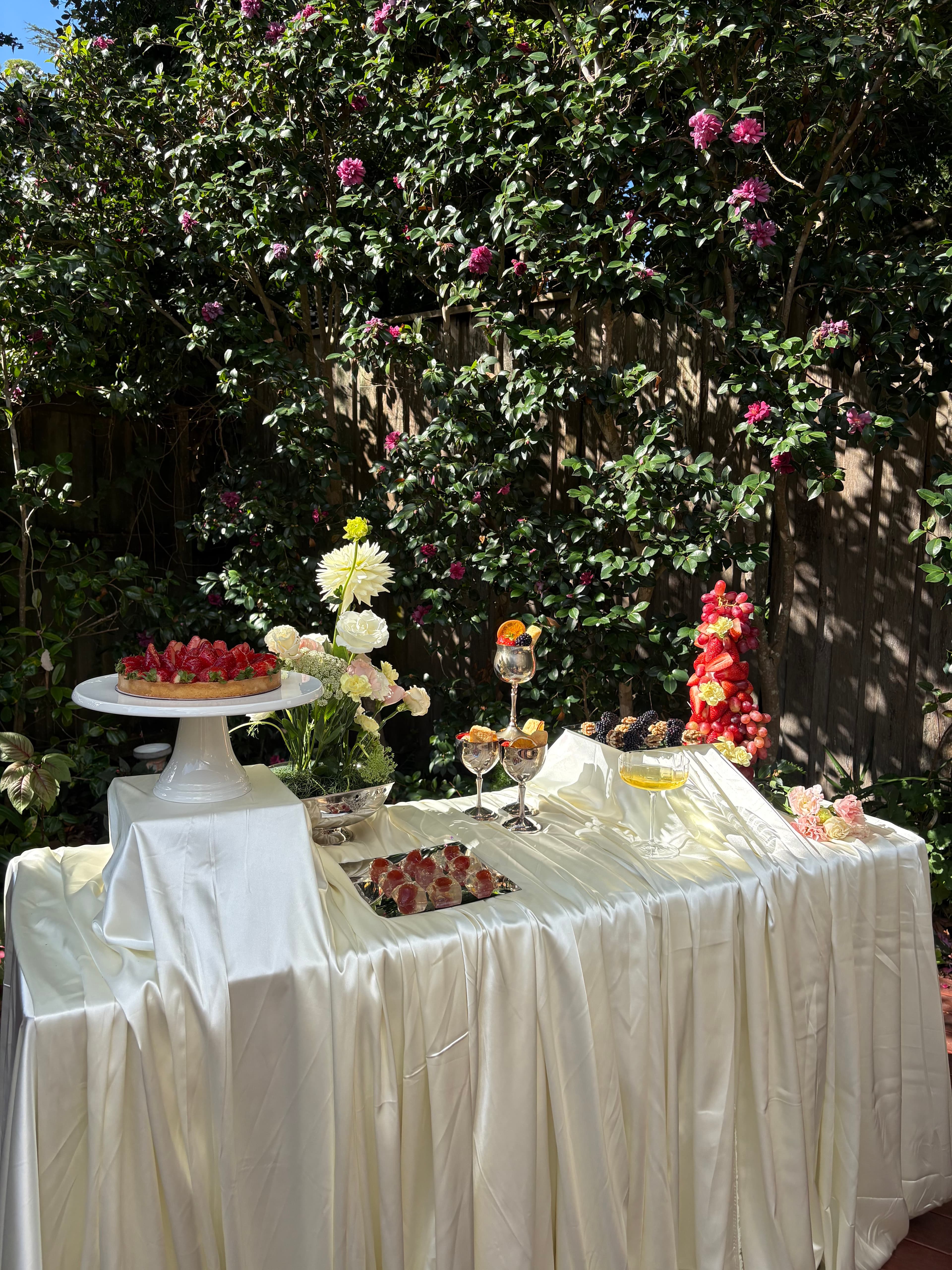 Styled outdoor wedding table with florals, fruit, and draped linen